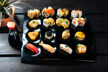 Rainbow Sushi Roll with salmon, eel, tuna, avocado, royal prawn, cream cheese Philadelphia, caviar tobica, chuka. Sushi menu on a black wood background