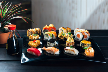 Rainbow Sushi Roll with salmon, eel, tuna, avocado, royal prawn, cream cheese Philadelphia, caviar tobica, chuka. Sushi menu on a black wood background