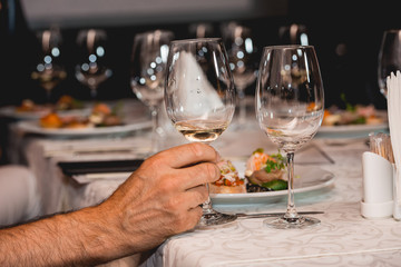 man holds glass of red wine. people consider the color of the wine and try how it smells in different glasses