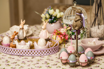 Beautiful Easter pastel decorations with table setting. Porcelain rabbits and Easter eggs.