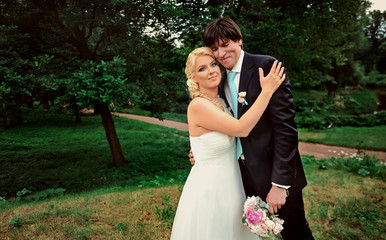 Bride and groom at wedding Day walking Outdoors on summer nature. Bridal couple, Happy Newlywed woman and man embracing in green park. Loving wedding couple outdoor. Bride and groom in honeymoon