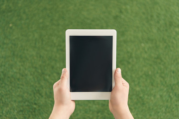 cropped shot of man holding tablet against green grass