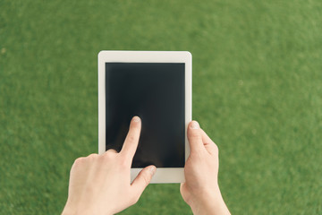 cropped shot of man using tablet against green grass