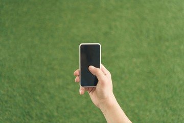cropped shot of man using smartphone against green grass