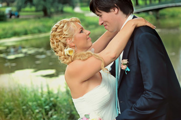 Fototapeta premium Bride and groom at wedding Day walking Outdoors on summer nature. Bridal couple, Happy Newlywed woman and man embracing in green park. Loving wedding couple outdoor. Bride and groom in honeymoon