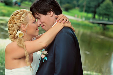Bride and groom at wedding Day walking Outdoors on summer nature. Bridal couple, Happy Newlywed woman and man embracing in green park. Loving wedding couple outdoor. Bride and groom in honeymoon
