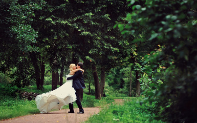 Fototapeta premium Bride and groom at wedding Day walking Outdoors on summer nature. Bridal couple, Happy Newlywed woman and man embracing in green park. Loving wedding couple outdoor. Bride and groom in honeymoon