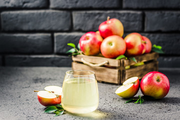 Homemade apple wine and fresh apples in wooden box on concrete background. Selective focus, space for text.