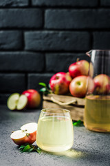 Fermented apple cider and fresh apples in wooden box on concrete background. Selective focus, space for text.