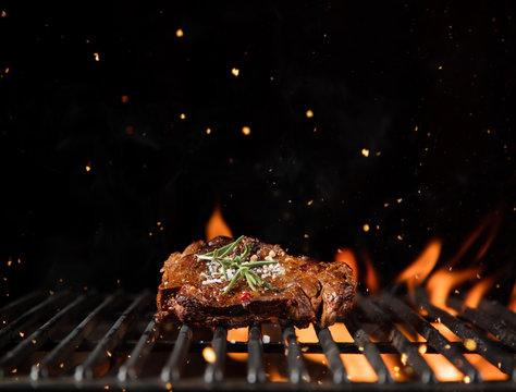 Fiery grill grid with piece of beef steak.