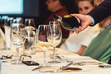 sommelier pouring white wine into glass at wine tasting