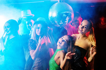 Dance party with group people dancing. Women and men have fun in night club. Back light on girls hair. People in brilliant suits dance under influence of alcohol. Toning and blur for background.