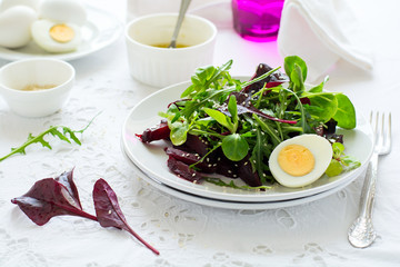 Fresh salad with beetroot, mix leaves, olive oil, egg and sesame seeds on white table cloth