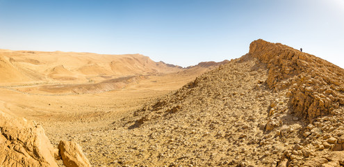 Backpacker tourist walking desert mountain cliff ridge edge landscape.