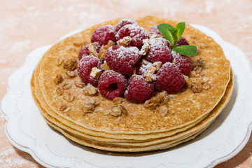 traditional thin pancakes with fresh raspberries on plate, closeup
