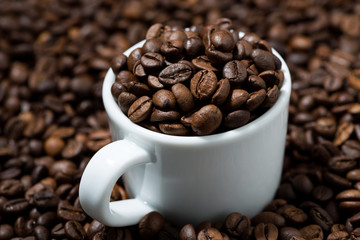 white cup in coffee beans, concept photo, closeup