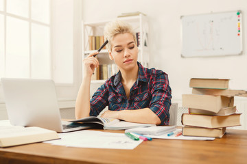 Student girl studying at table full of books