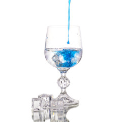 Crystal glass with soda and ice with blue water on a white background