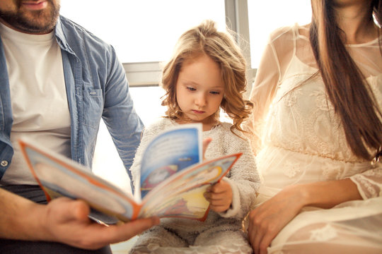 happy family reading a book to her daughter. Mothers Day.