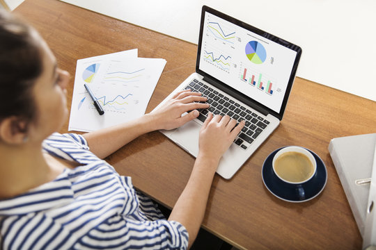 Young woman working on charts on her laptop at home
