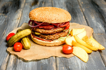 Burger with beef cutlet and fresh vegetables fried potato on wooden background