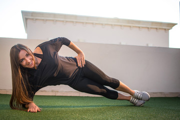 Young sporty woman doing side plank outdoors.