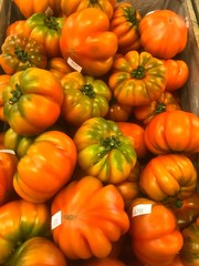 Pile of beautiful red and green heritage tomatoes in market stall, home grown organic tomatoes, large ripe fruit and vegetables in farmers market, homegrown produce, healthy eating, Mediterranean die 