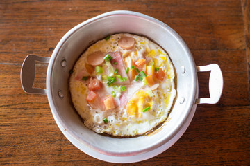 breakfast with fried eggs in a pan on wooden background