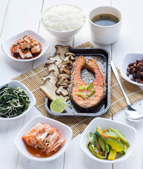 Grill salmon steak with mushroom and lemon in steel plate, some slide dish and seaweed soup on wood table