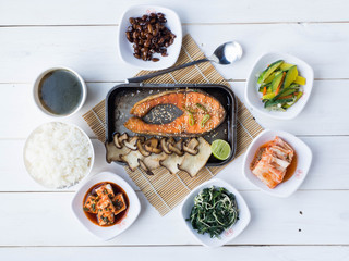 Grill salmon steak with mushroom and lemon in steel plate, some slide dish and seaweed soup on wood table