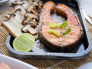 Grill salmon steak with mushroom and lemon in steel plate, on wood table