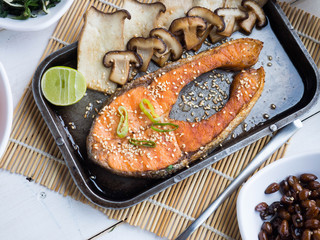 Grill salmon steak with mushroom and lemon in steel plate, some slide dish and seaweed soup on wood table