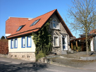 Restauriertes kleines altes Haus mit spitzem Giebel vor blauem Himmel im Sonnenschein an der...