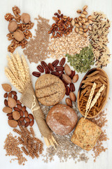 Food with high fibre content with whole grain bread rolls, whole wheat pasta, grains, nuts, seeds and cereals. Concept of foods high in antioxidants, omega 3 and vitamins. Rustic background top view.