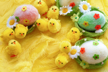 Fototapeta na wymiar Baby yellow Easter toys chicks and eggs on a background of feathers. Festive greeting card