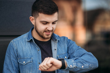Obraz premium Handsome man in a denim shirt uses a phone standing on the street