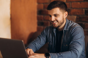 Man with a beard uses a laptop in a cafe