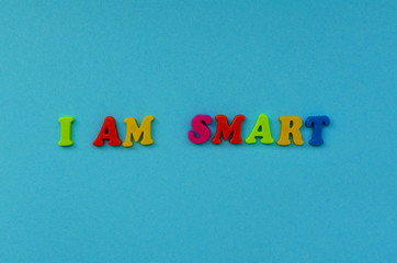 colorful text  'i am smart"  of magnetic letters on blue paper background