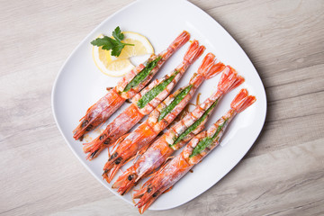 Baked langoustines on a white plate. Selective focus, close-up.