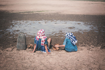 Sad boy and girl sitting on cracked dry ground, Concept drought and shortage of water crisis