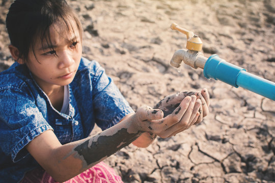 Sad girl want to drink some water on crack ground , Concept drought and shortage of water crisis