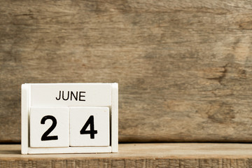 White block calendar present date 24 and month June on wood background