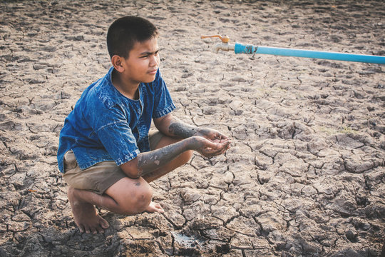 Sad boy want to drink some water on crack ground , Concept drought and shortage of water crisis