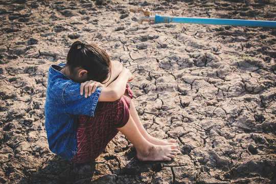 Sad girl want to drink some water on crack ground , Concept drought and shortage of water crisis