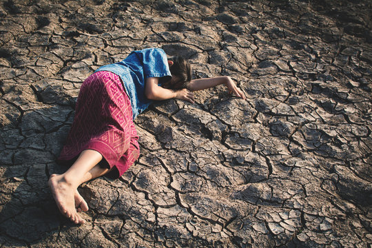 Sad girl tired and exhausted on cracked dry ground , Concept drought and shortage of water crisis