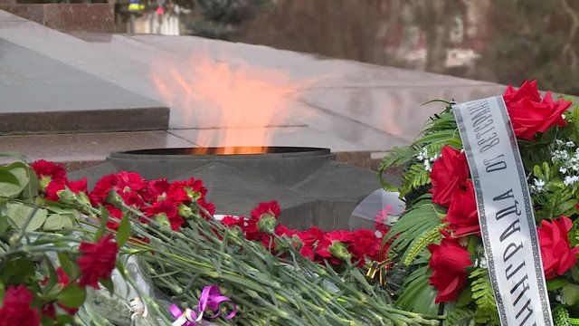 Red flowers lie on memorial. Tribute to the memory of victims in the Great Patriotic War. Grave of died soldiers. Russian letters on the wreaths of memory