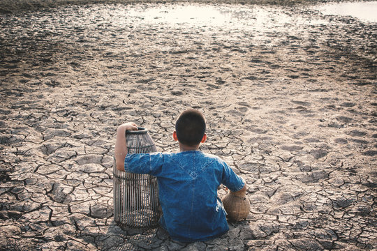 Sad boy tired and exhausted on cracked dry ground , Concept drought and shortage of water crisis