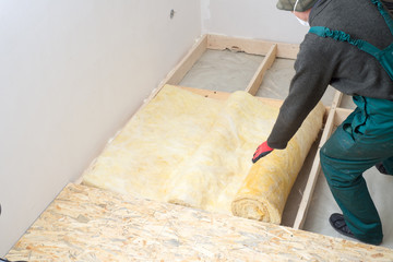 worker insulates the floor with mineral wool