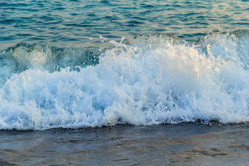 Sea wave, water, foam runs over the shore at sunset. Background. Texture