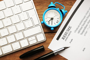 Resume or curriculum vitae on a wooden desk near a computer keyboard
